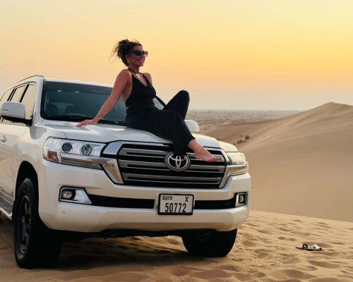 girl sitting on front side of car and taking picture during Desert Safari Trip in Abu Dhabi